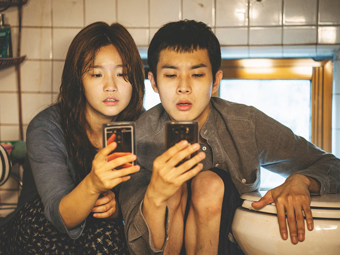 chica y chico chinos mirando sus móviles escena de la película Parásitos